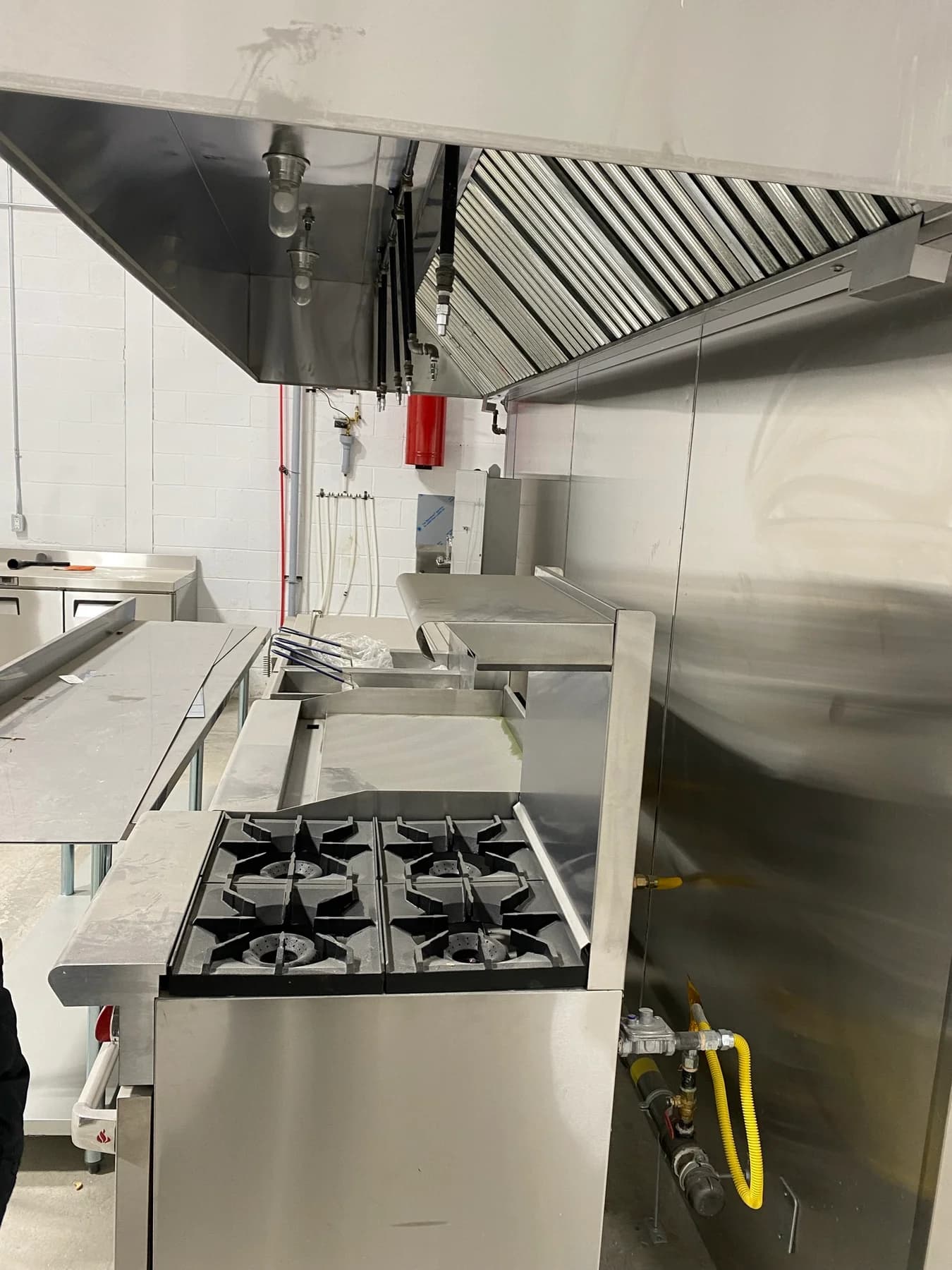 APEX installation-stage cooking line with stainless-steel equipment beneath a commercial exhaust hood