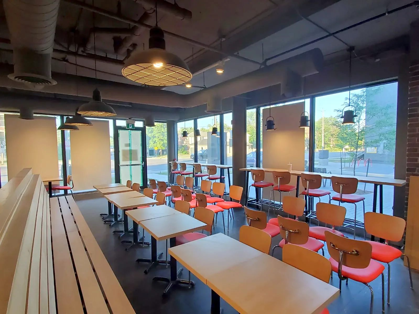 Finished restaurant dining room with timber tables, red chairs and bench seating by the windows