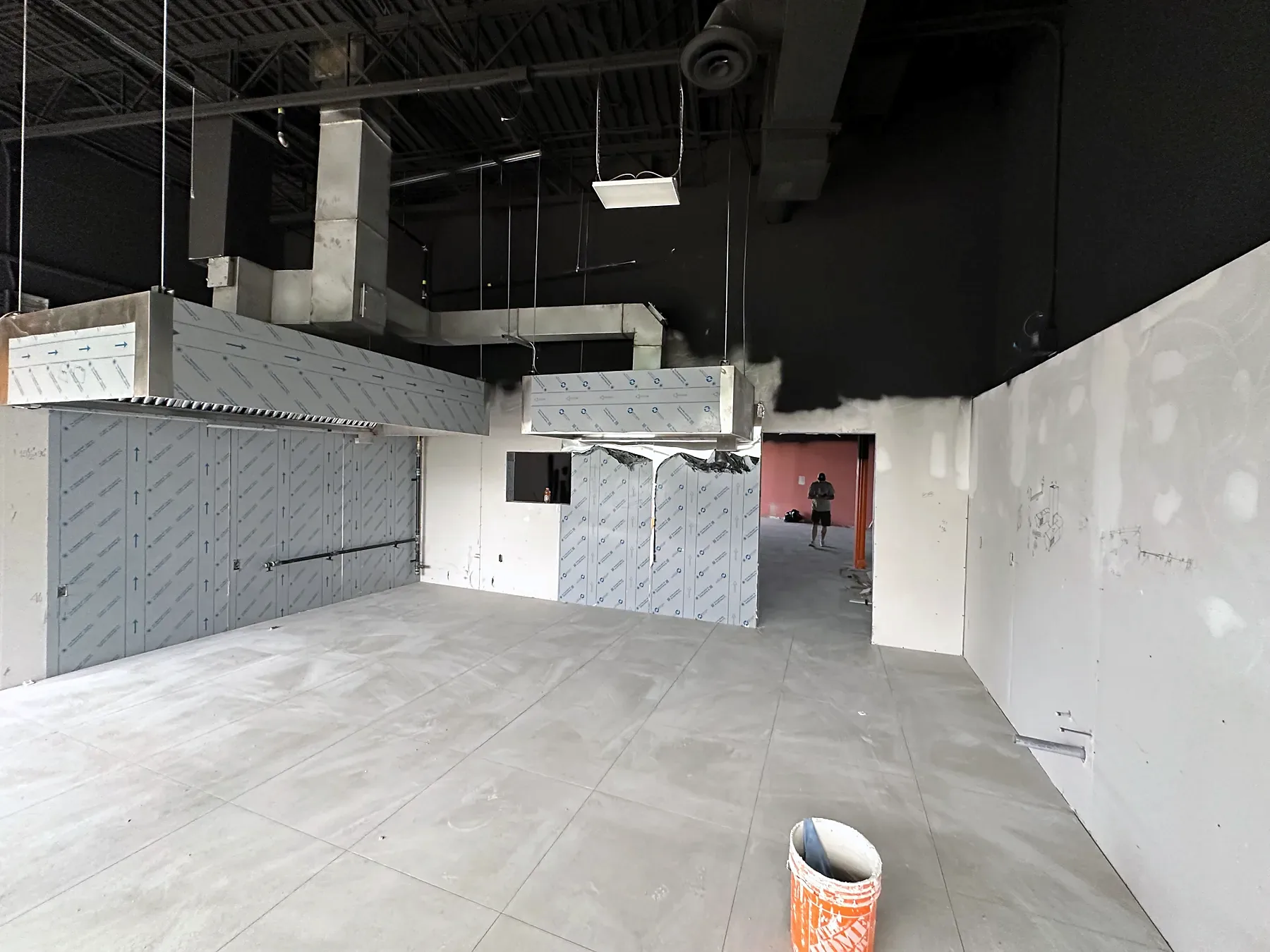 Empty commercial unit with a new exhaust hood frame and wall panels before the kitchen fit-out