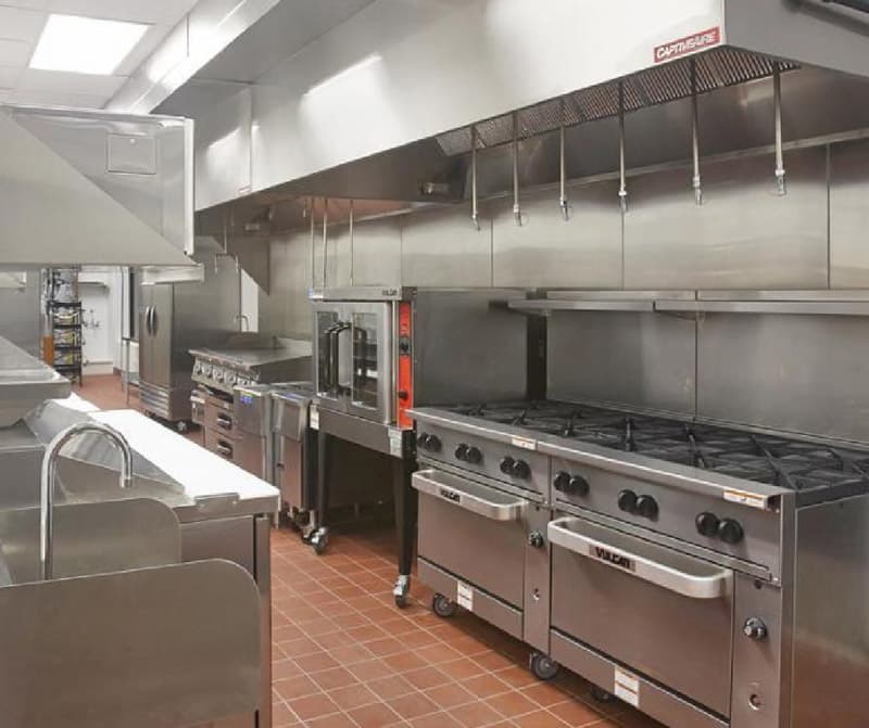Completed stainless-steel cooking line beneath a commercial exhaust hood